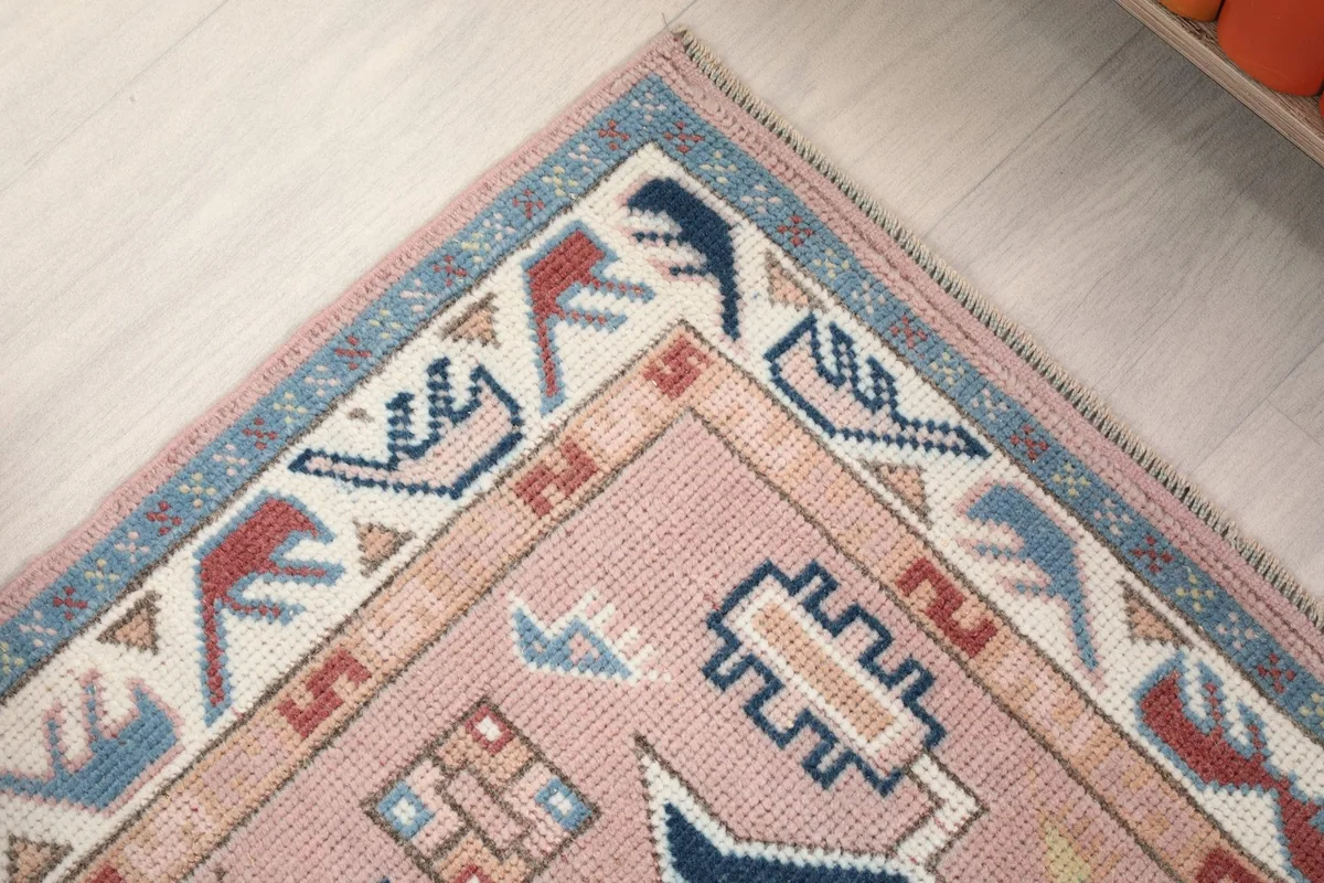 Detailed view of the rug's border design, featuring intricate blue and ivory tribal patterns.