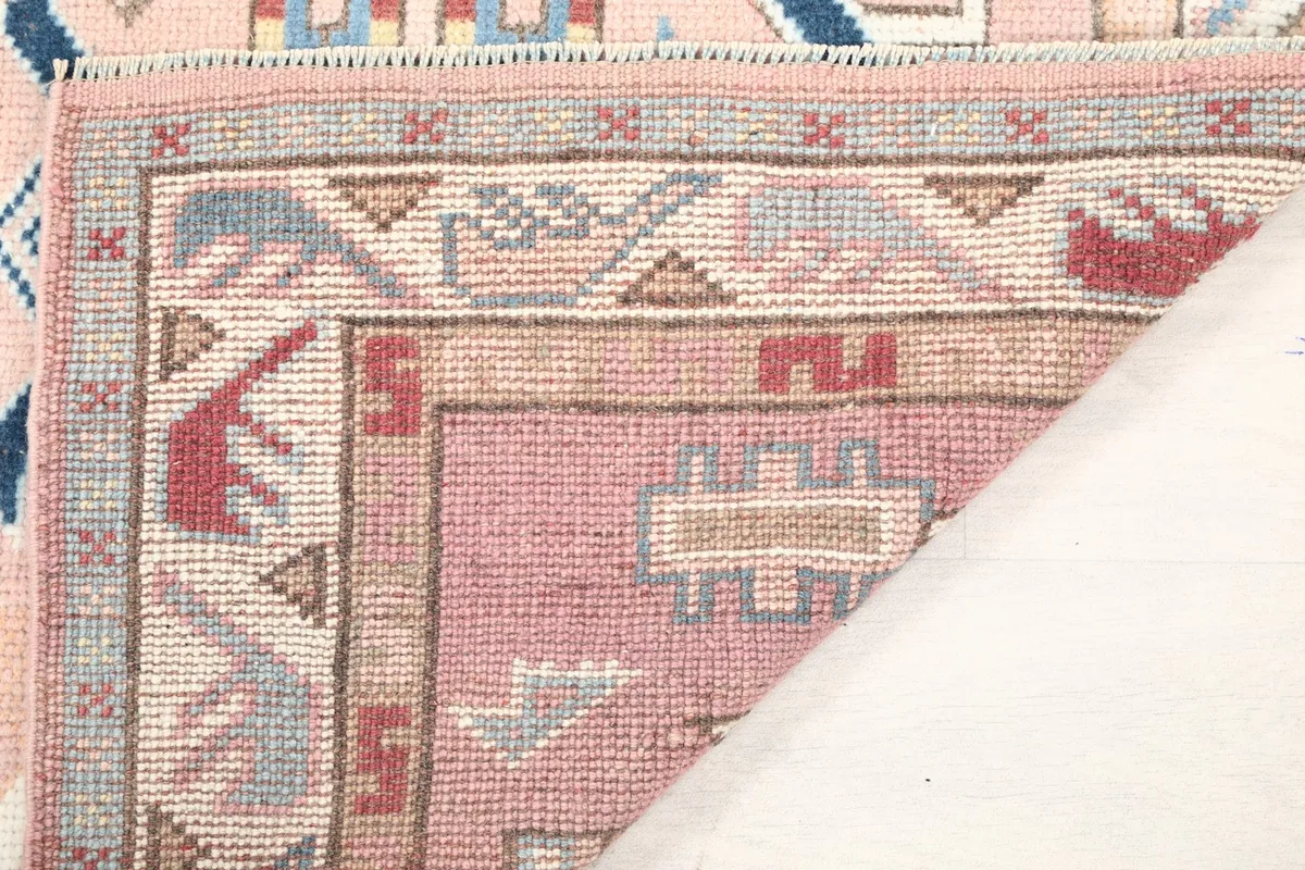 Folded corner of the rug, revealing the pile thickness and the quality of the wool material.