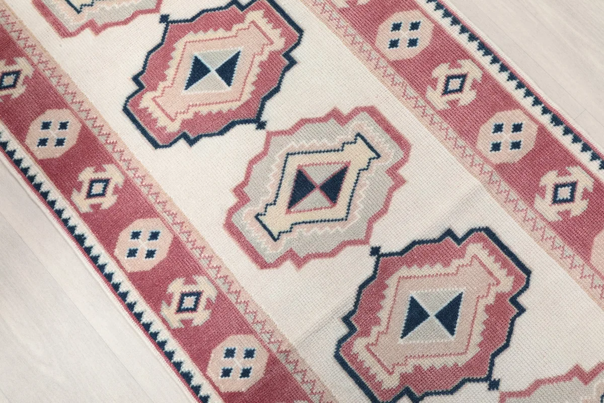 Oblique view showcasing the repeating geometric medallions in rose, navy, and ivory.