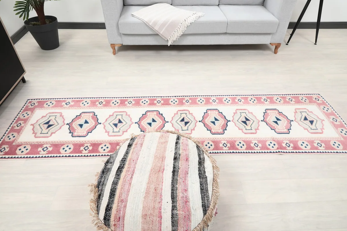 Full length view of the runner rug in a room, with an ottoman in the foreground.
