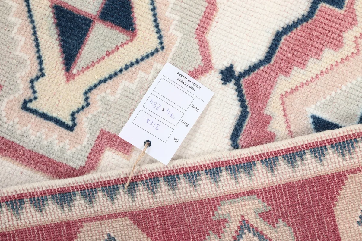 Close-up detail of the rug's texture and a product tag, showing the wool pile.
