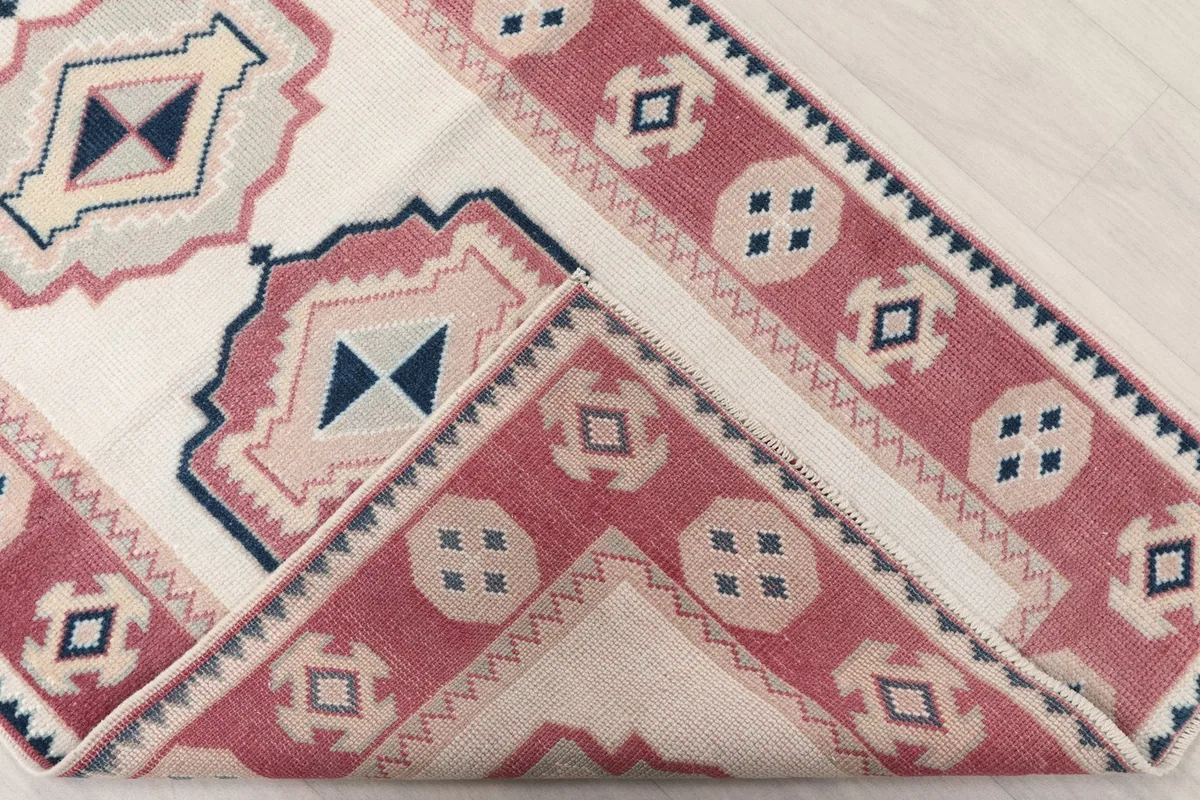 Folded corner of the rug, revealing the wool pile and cotton foundation.