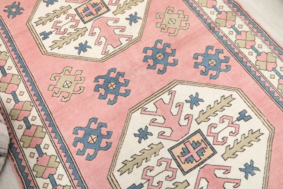 Close-up of the central medallion and surrounding tribal motifs in rose, ivory, blue, and olive