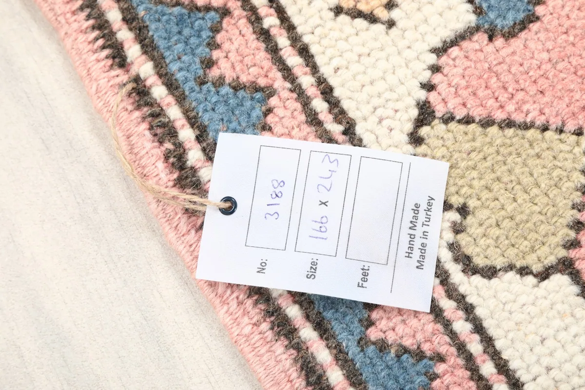 Close-up of the rug's low pile and a tag showing its dimensions and handmade origin