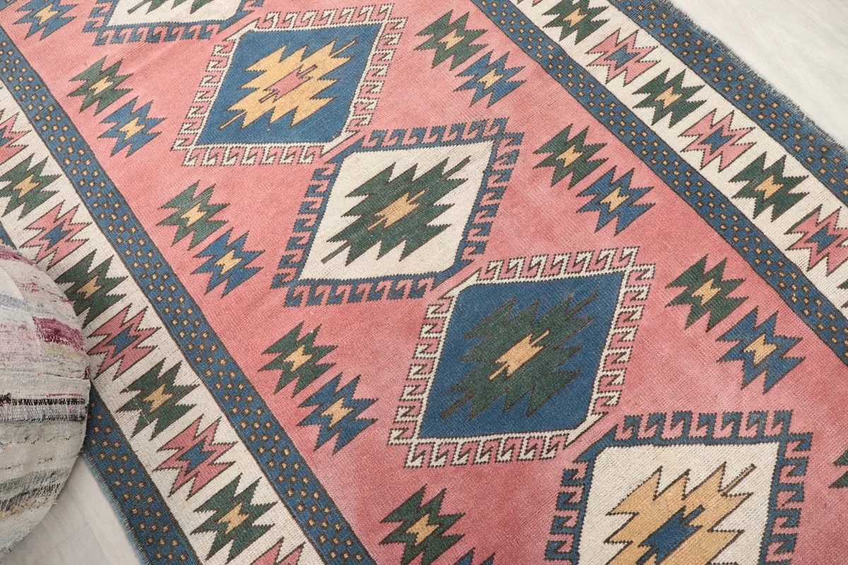Diagonal view across the rug, highlighting the row of diamond-shaped geometric medallions