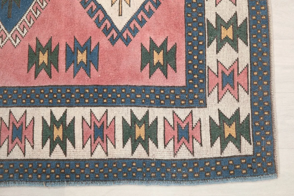 Detailed view of the rug's corner with navy and ivory border patterns and small fringe