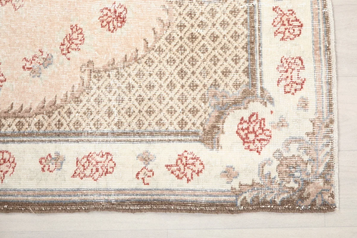 Detailed view of the rug's border with geometric patterns and corner floral accents