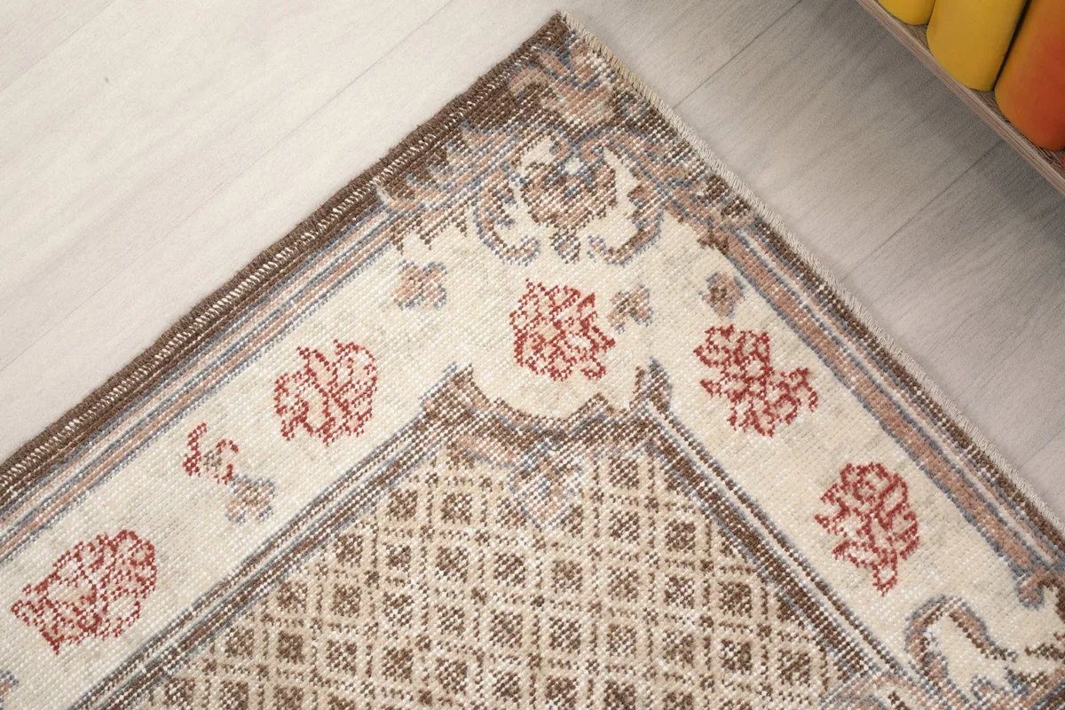 Corner detail of the rug's brown and gray geometric border and ivory field
