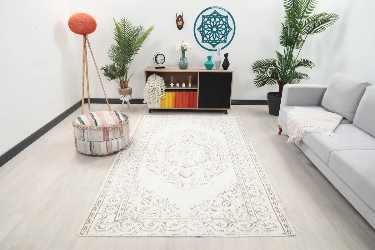 Ivory vintage Anatolian rug in a living room setting, showing its scale with a sofa and decor.