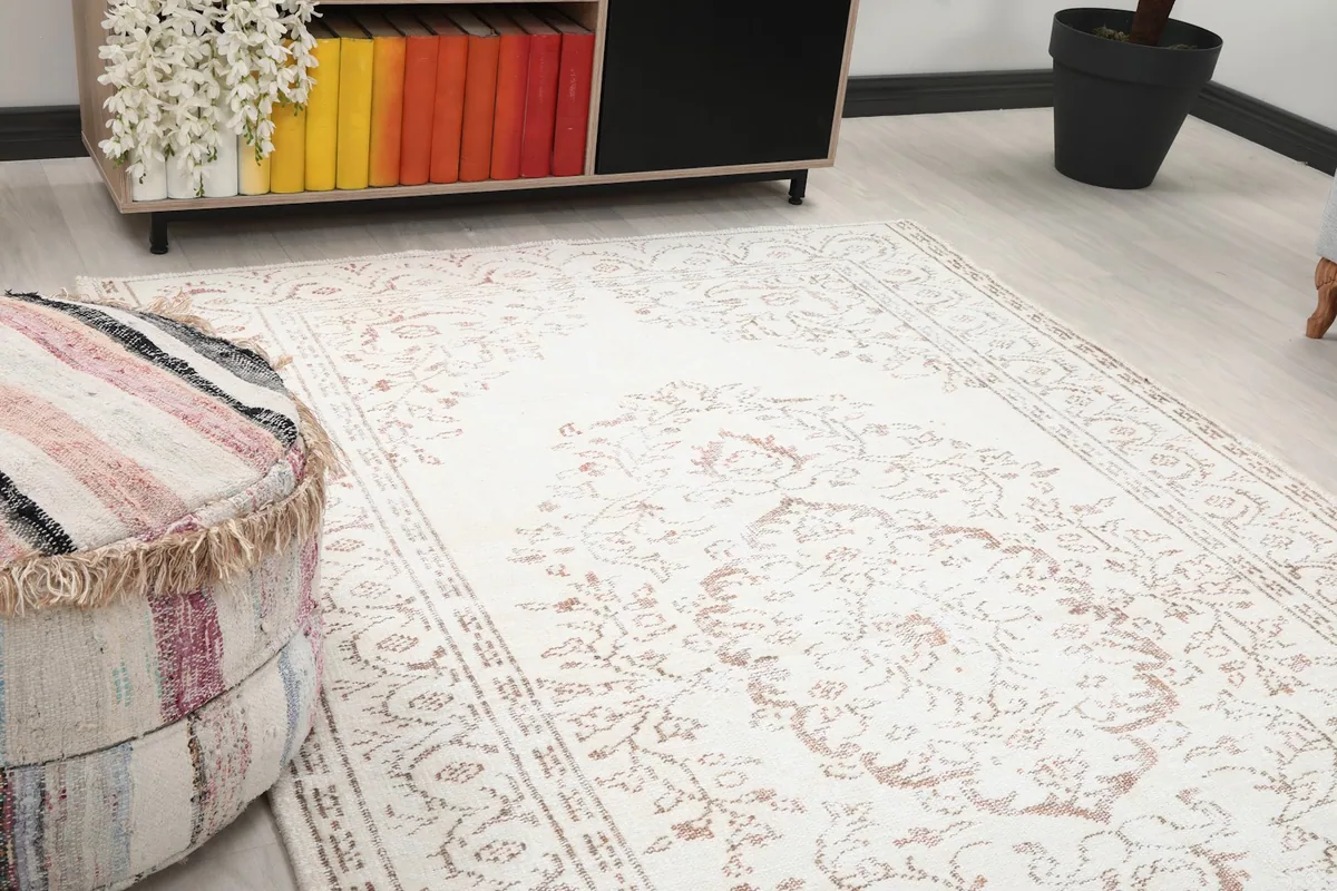 Close-up of the rug's central floral medallion and surrounding patterns, showing subtle beige tones.