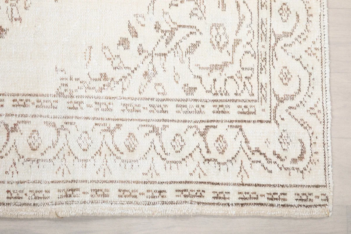 Detail of the rug's corner, showcasing the intricate beige and tan border design and field pattern.