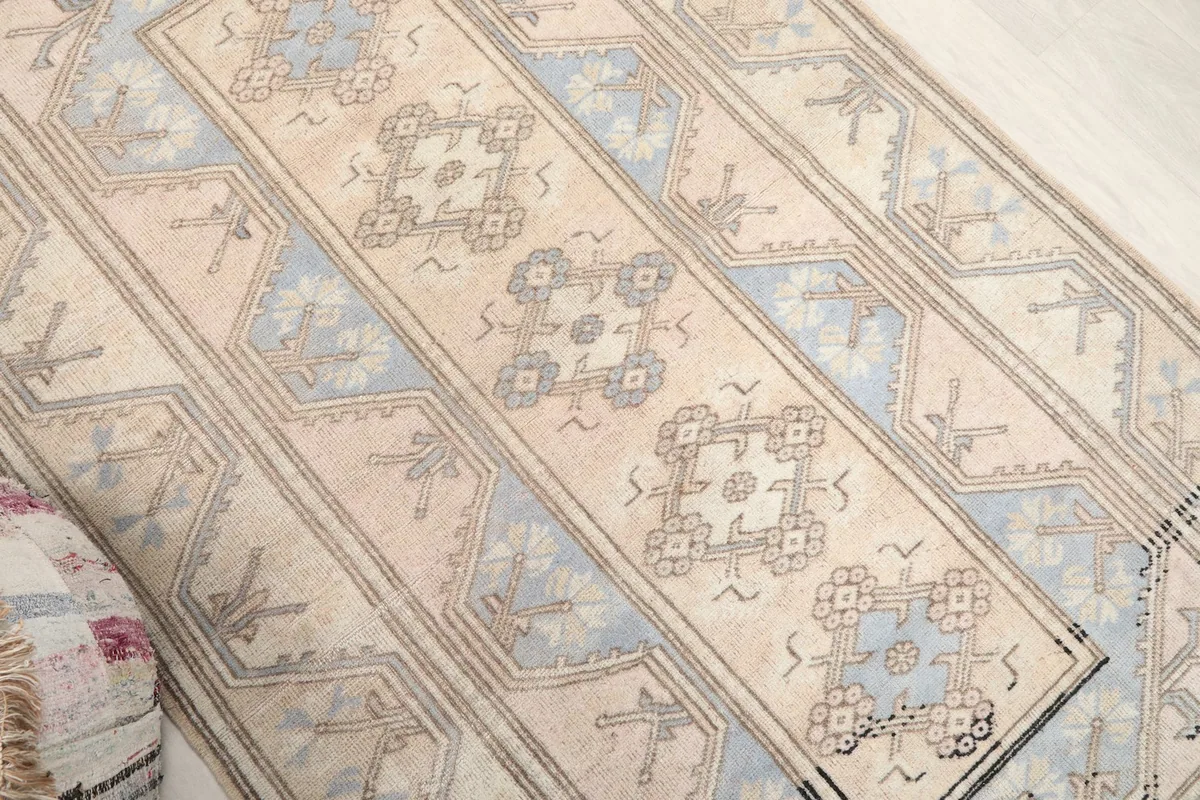 Diagonal view of the rug, highlighting the central cream field and surrounding blue and gray geometric designs.