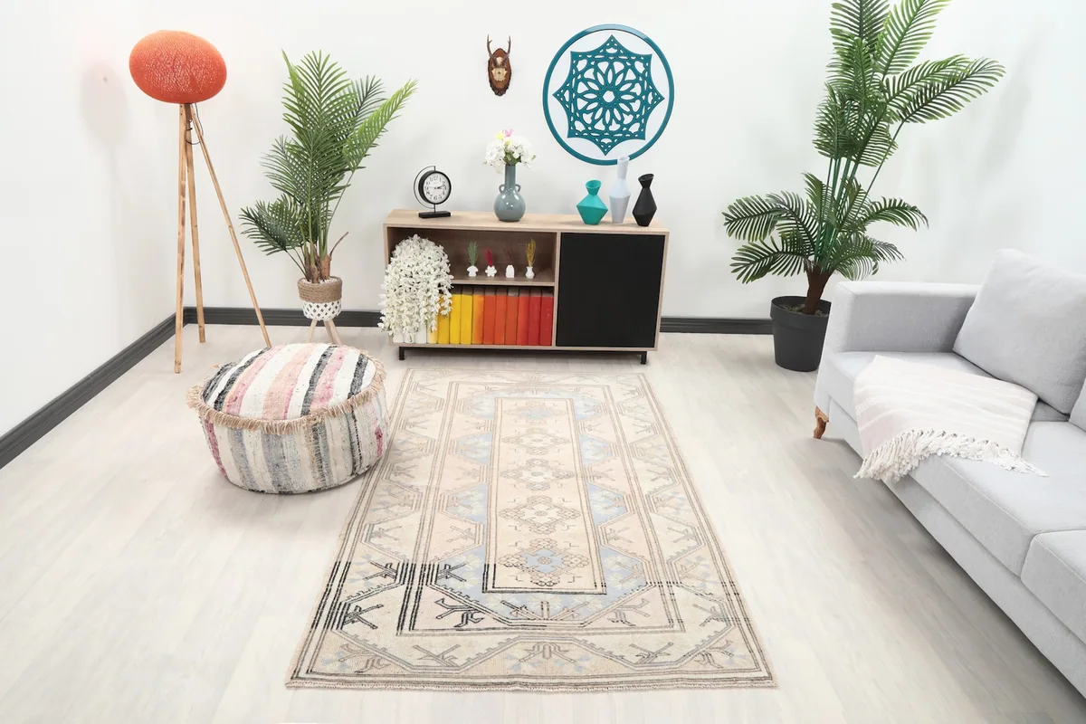 Vintage cream and blue rug displayed in a bright living room setting with modern furniture.