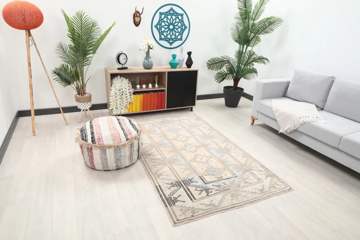 Angle view of the cream and blue area rug in a room, showing its placement relative to a sofa and ottoman.