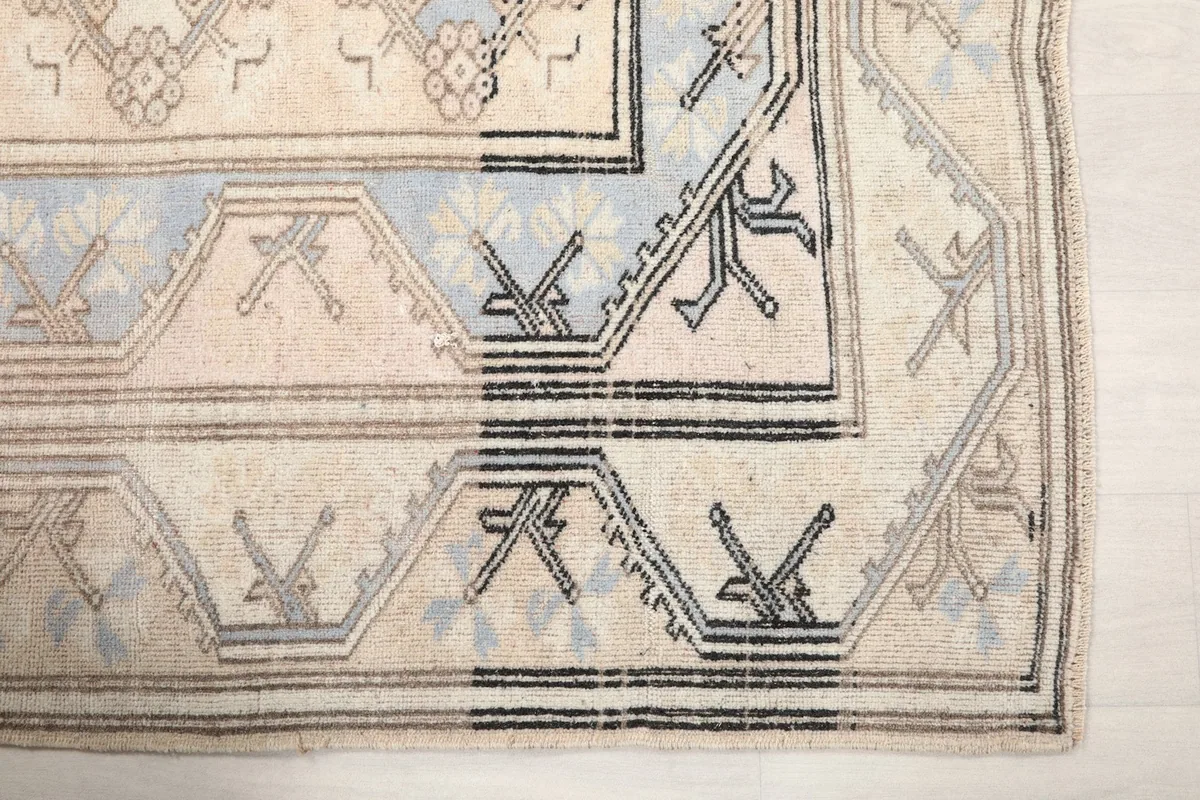 Detailed view of the rug's corner with black and gray tribal patterns in the border.