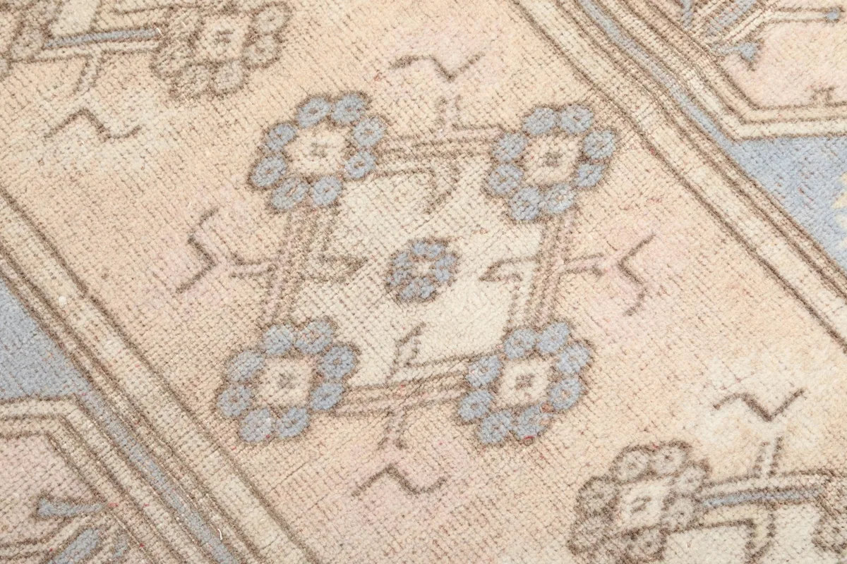 Close-up of the hand-knotted wool pile, showing the detailed blue and gray floral-like motifs.