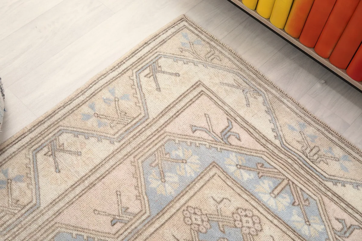 Corner detail of the rug, showcasing the intricate geometric border in cream, blue, and gray.