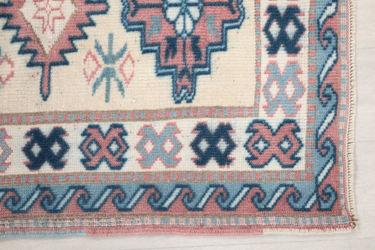 Detailed view of the corner of the rug, showing geometric motifs and border patterns