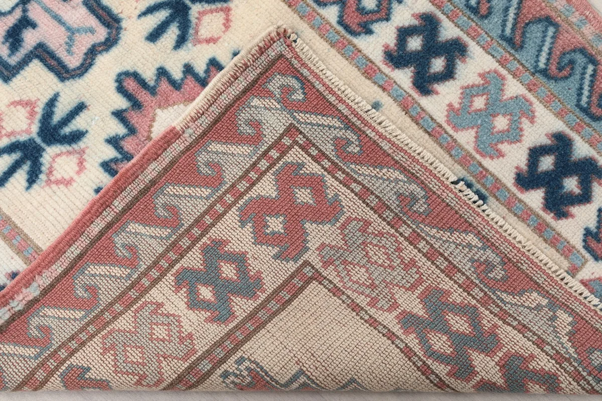 View of the back of the rug, folded to show the hand-knotted cotton foundation