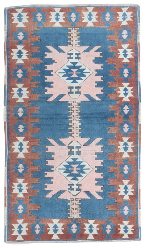 Full overhead view of the 4x6 vintage blue, rust, and pink geometric Anatolian rug on a white background.