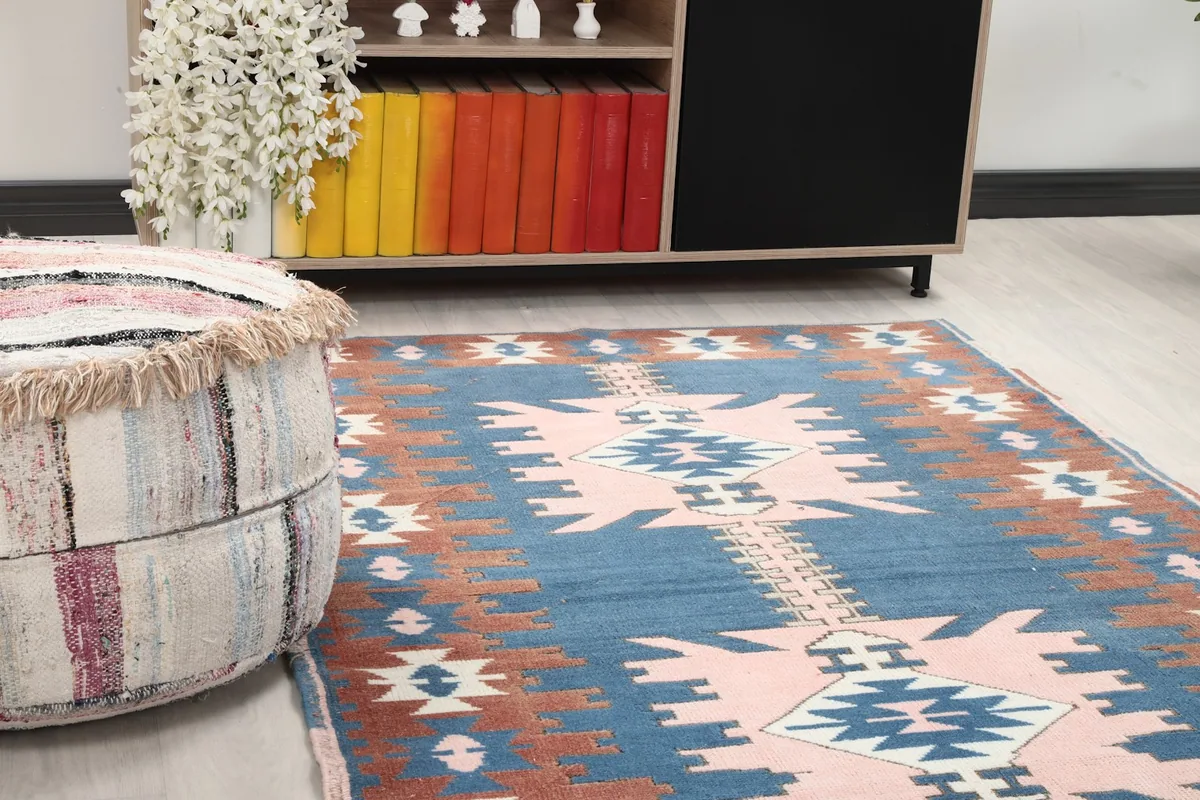 Close-up of the vintage rug's blue and pink central motifs, showing texture and colors in a room setting.