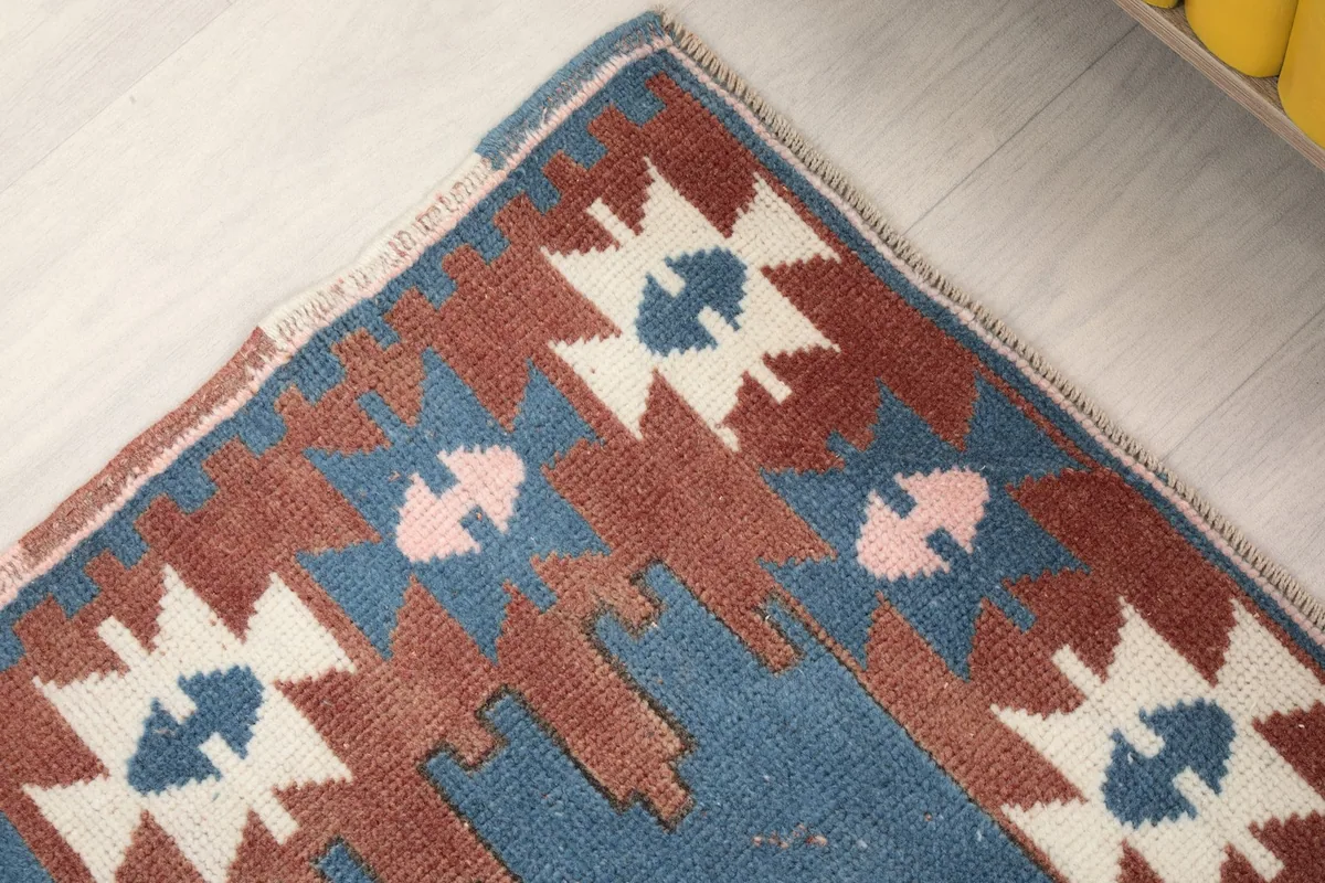 Corner detail of the rug, showing the wool pile, fringe, and the transition from border to field.