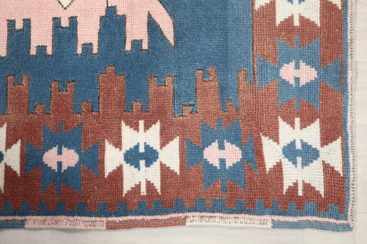 Detailed view of the rust-colored border with geometric patterns and the blue field of the Anatolian rug.