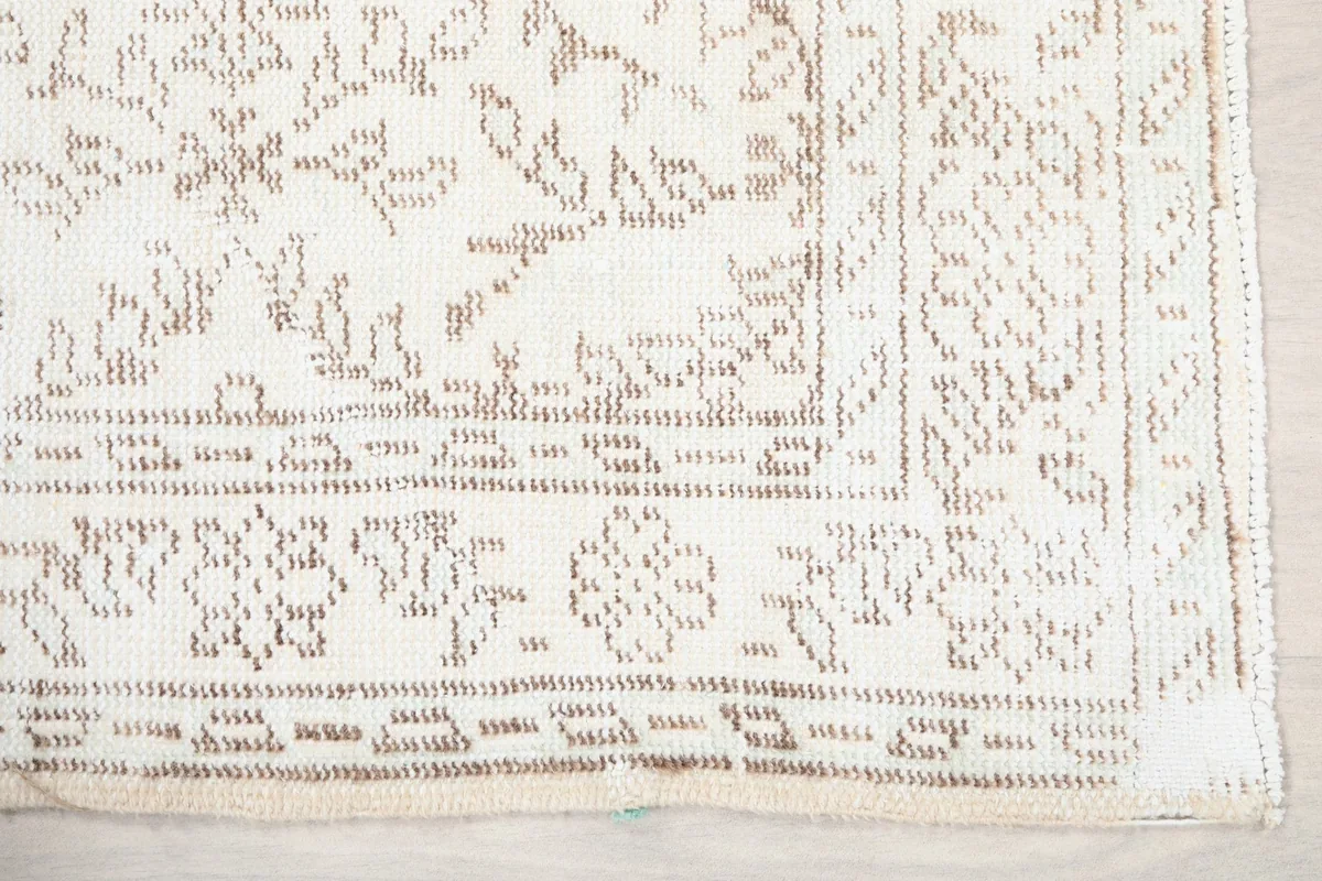Detail view of the rug's corner, showcasing the beige geometric border and subtle wear