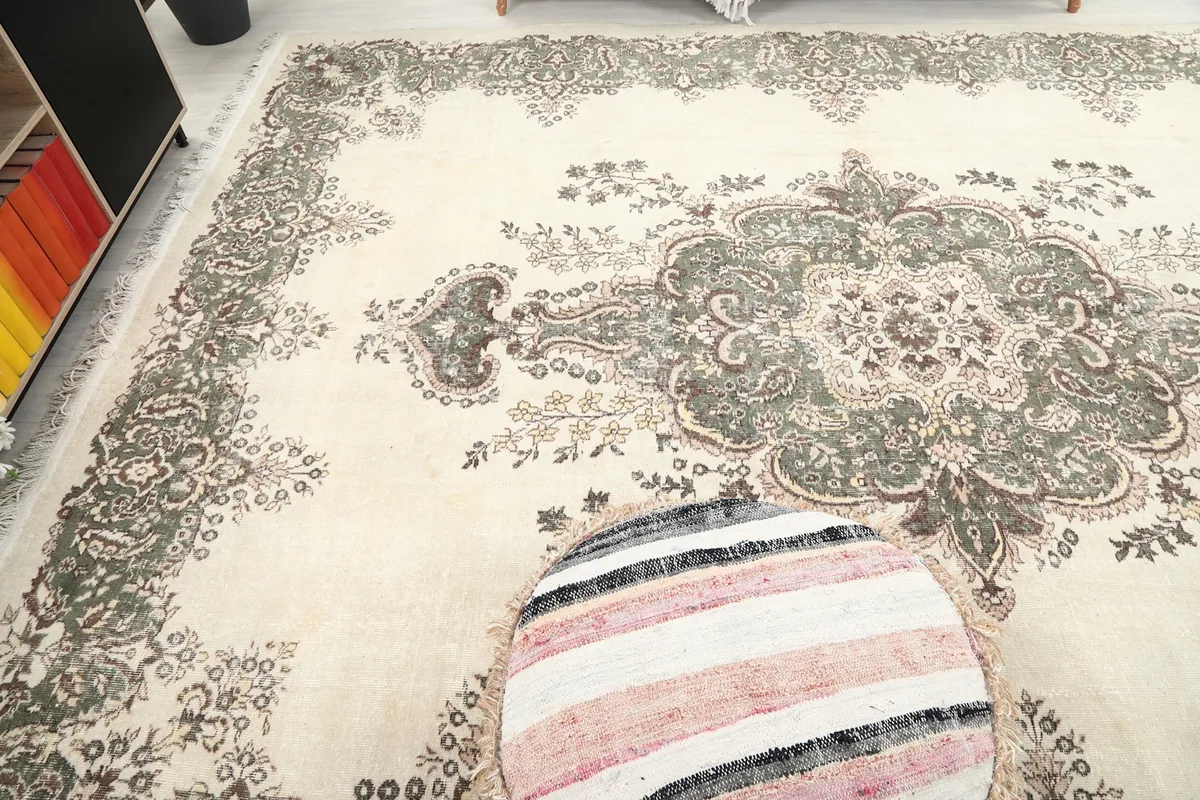 High-angle view showing the rug's surface, colors, and the subtle patina across the ivory field.