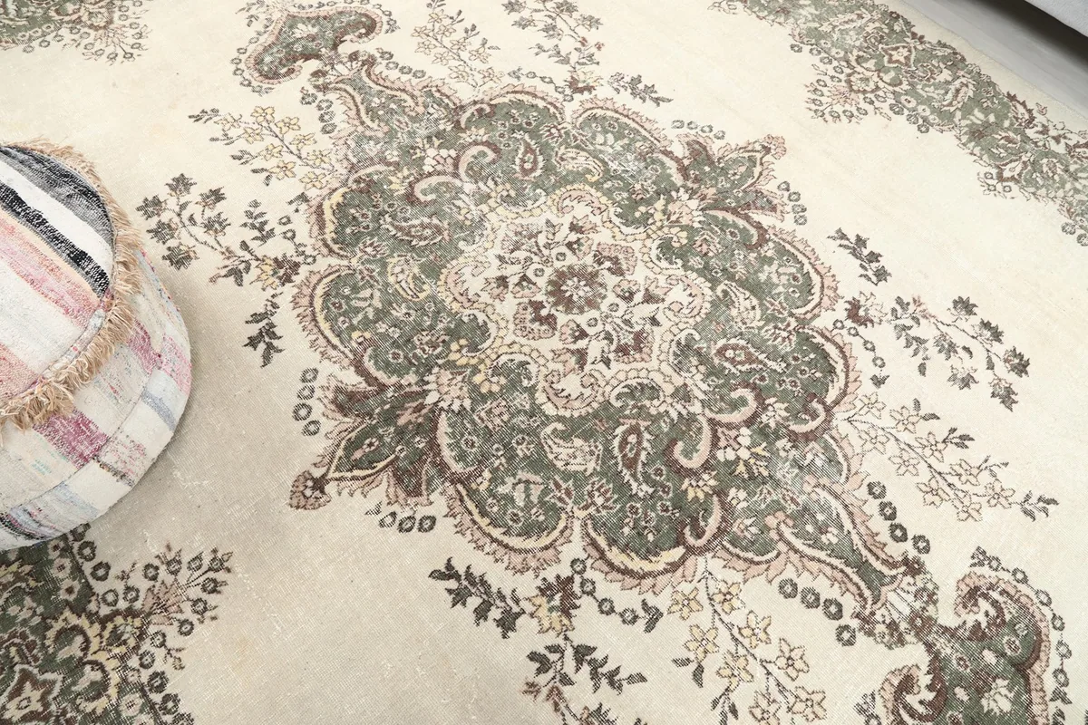 Detailed view of the central floral medallion on the ivory field, showing intricate green and rose patterns.