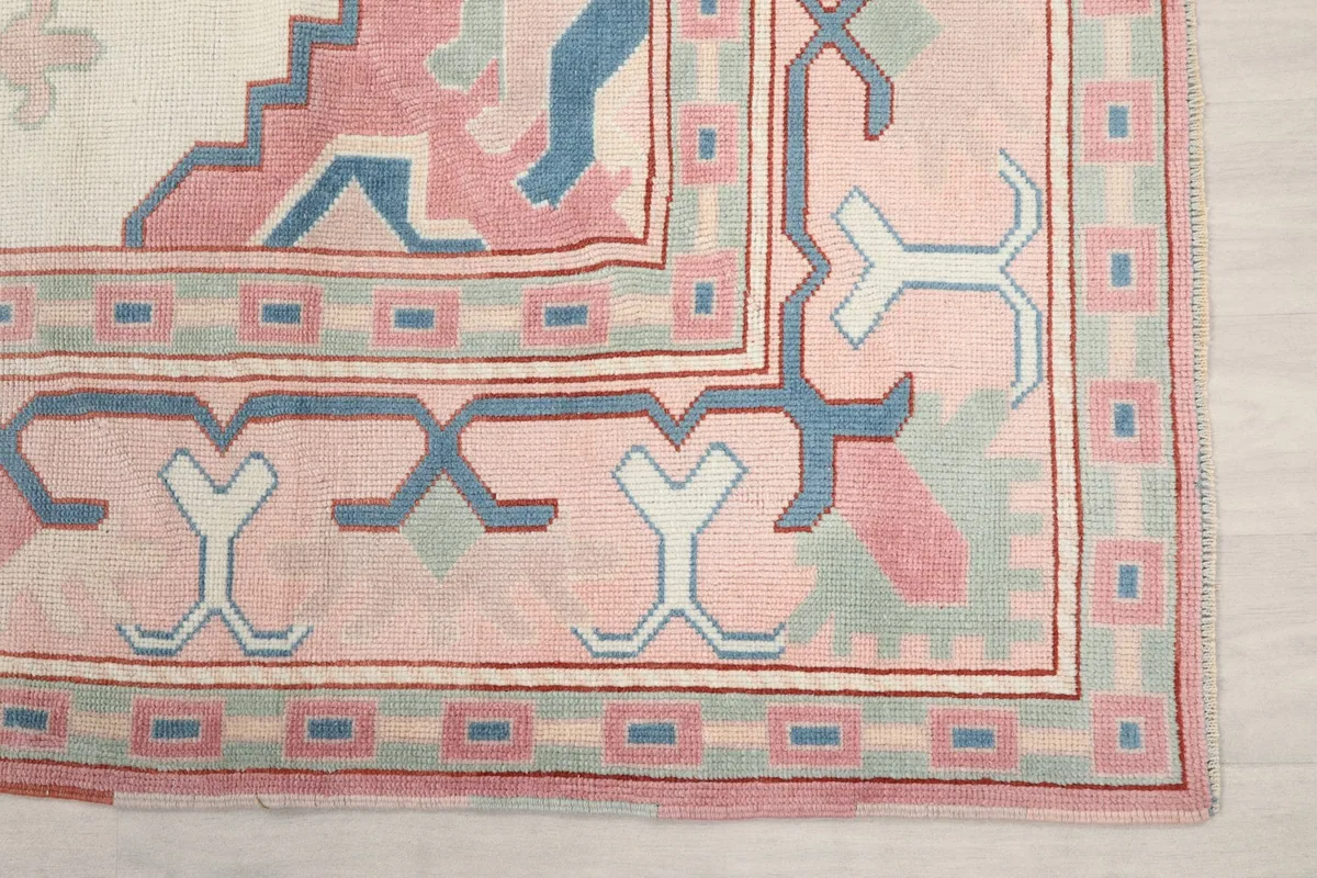 Detail of the rug's pink border with blue and cream geometric designs