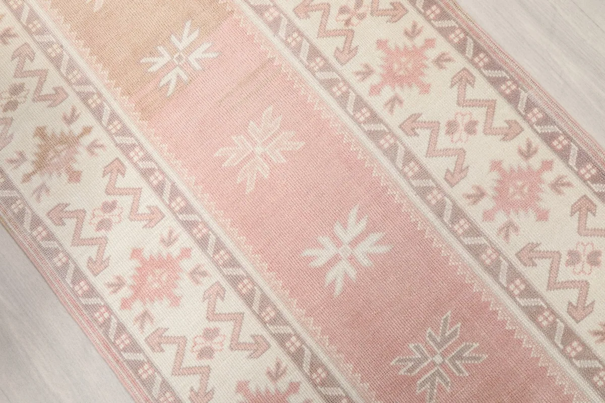 Diagonal overhead view capturing the rose field and beige geometric border of the runner