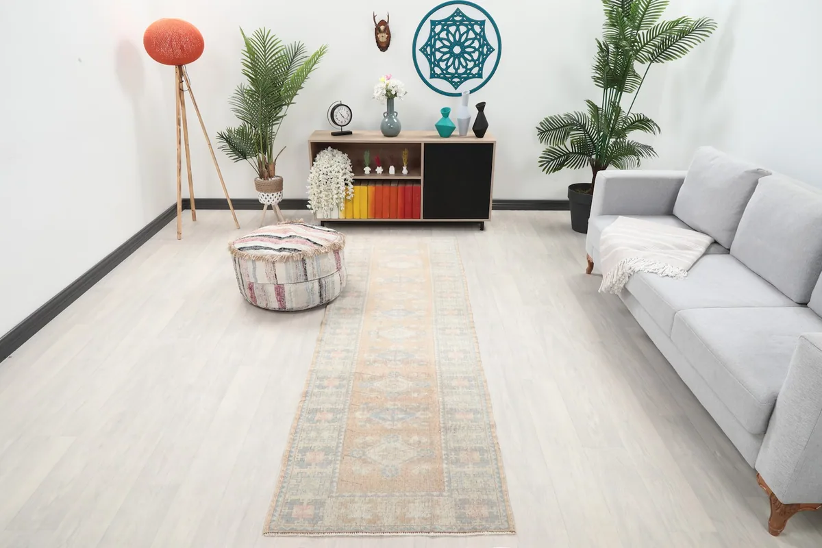Vintage tan runner rug displayed in a bright living room setting with a sofa and ottoman