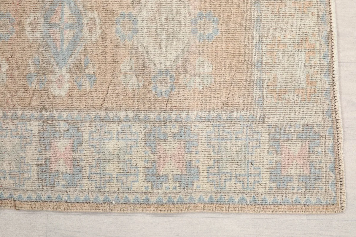 Detailed view of the rug's border showing gray and light blue geometric patterns