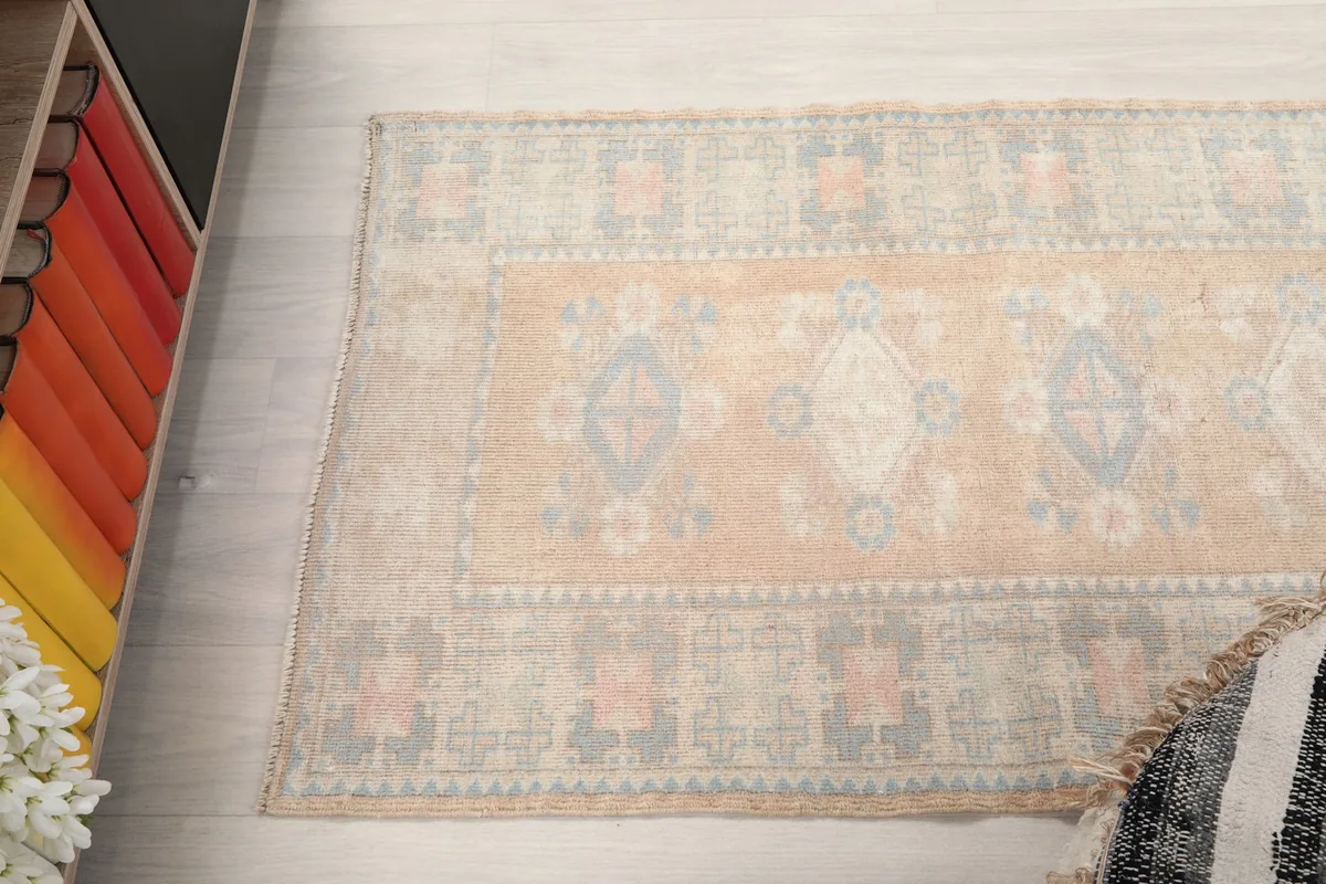 Overhead view focusing on the upper section of the tan runner rug with its geometric motifs