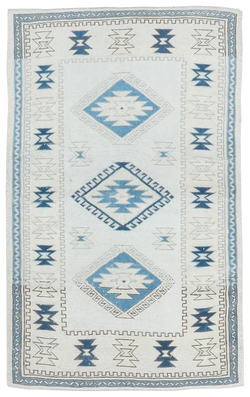 Full top view of the 4x7 ivory and blue tribal geometric vintage Anatolian rug on a white background.