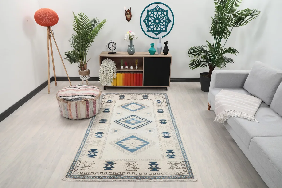 Ivory and blue vintage rug placed in a modern living room setting with a light sofa and wooden furniture.