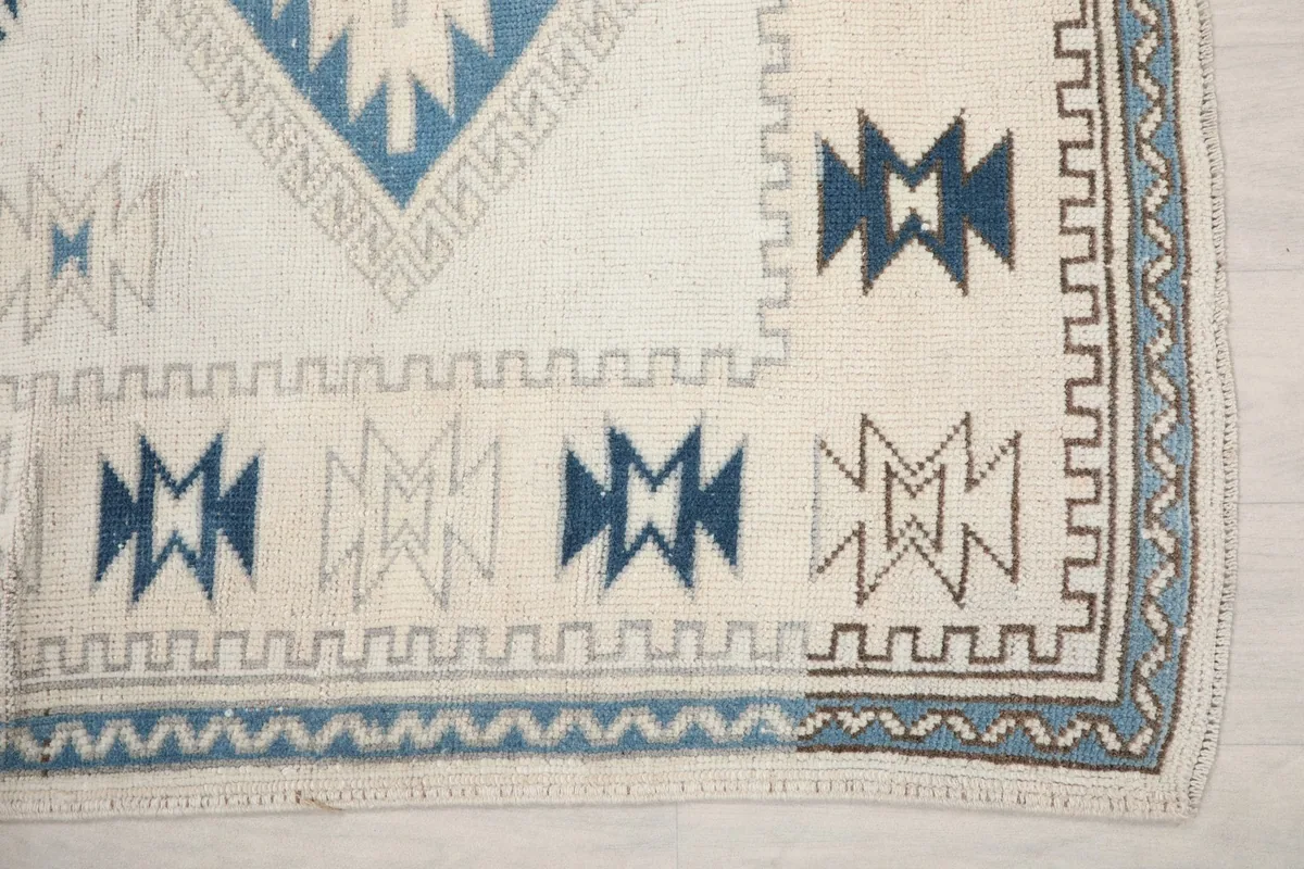 Detailed view of the rug's border and corner, highlighting the geometric patterns in blue and navy tones.