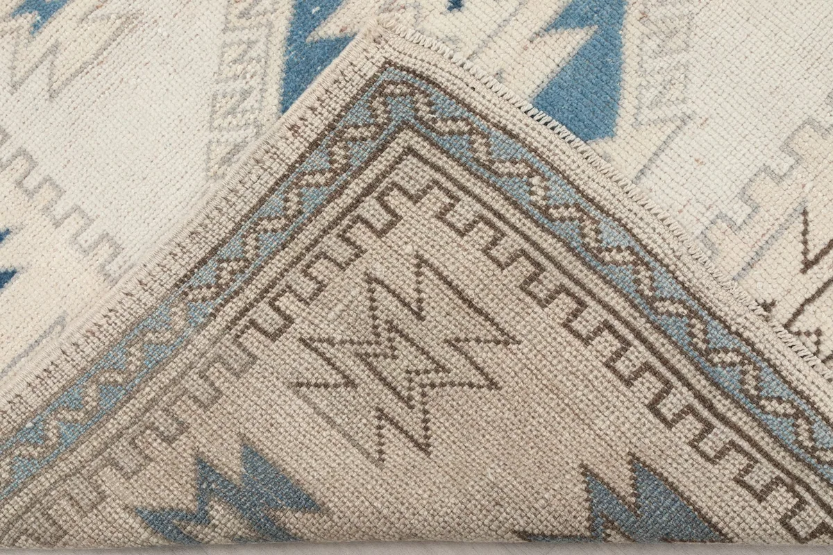 Corner of the rug folded back to show the cotton foundation and the reverse side of the hand-knotted wool.