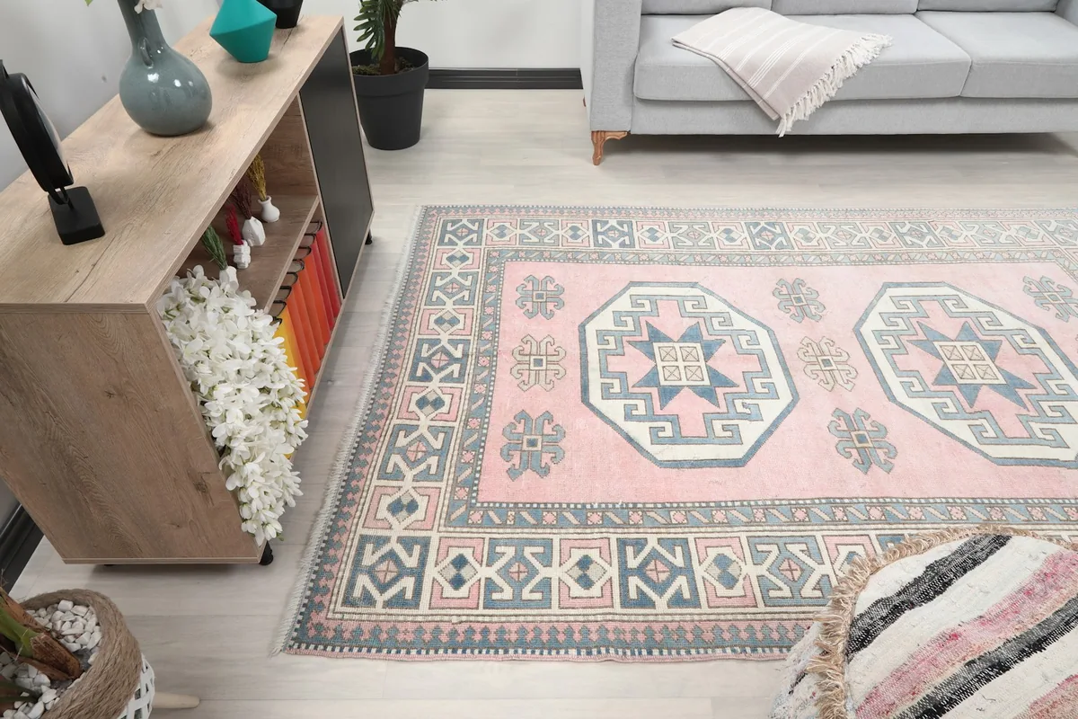 Wide angle view of the pink geometric rug in a living space with a side table and sofa.