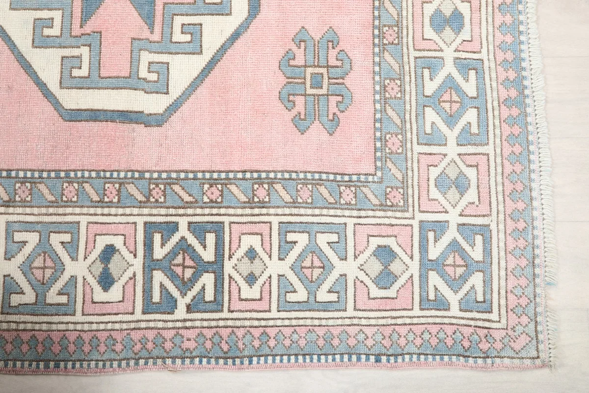 Detail of the rug's corner, showcasing the intricate blue and ivory geometric border design.