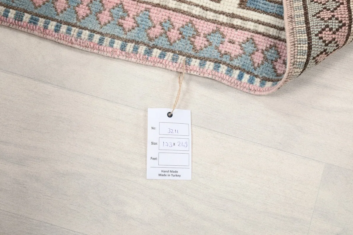 Photo of the rug's care tag, displaying its size 173x249 cm and origin.