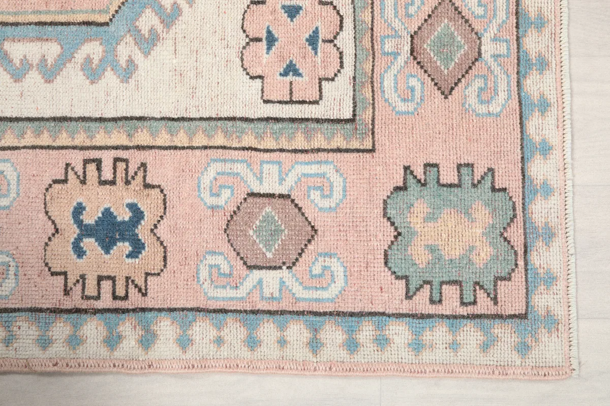 Detail of the Pink Geometric Anatolian Rug border, showing the pink field and blue and cream motifs.