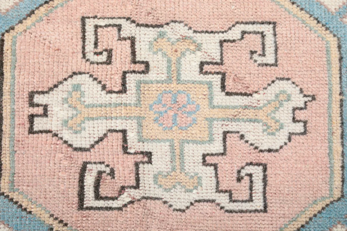 Close-up of a central medallion motif on the Pink Geometric Anatolian Rug, revealing knot detail and colors.