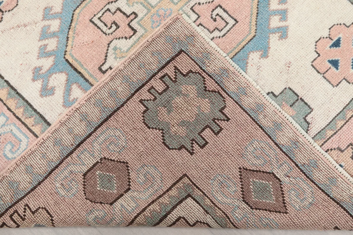 Folded corner of the Pink Geometric Anatolian Rug, showing the hand-knotted construction and wool pile.