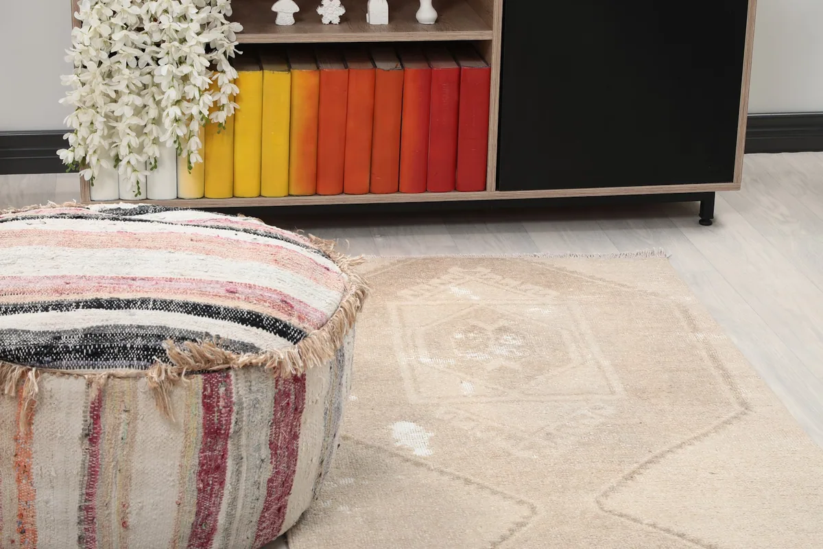 Close-up of the rug's pattern and texture next to a striped pouf in a room setting