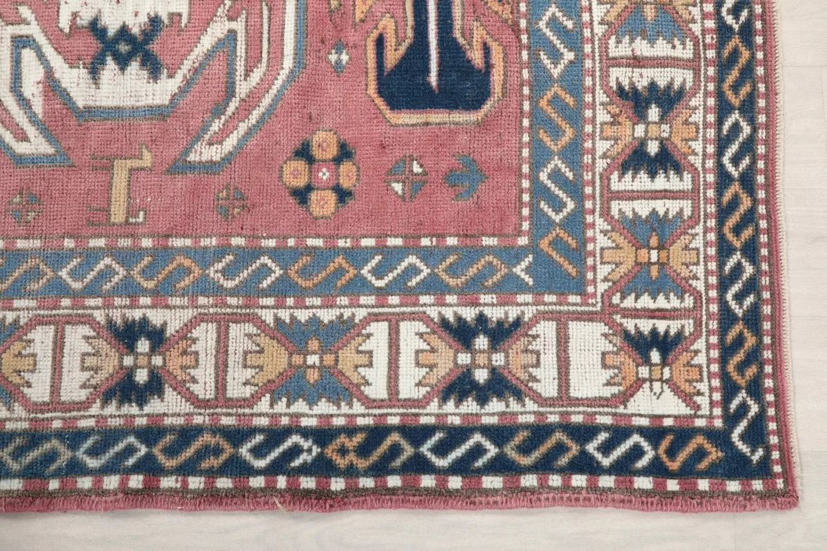 Detailed corner view of the rug's border, showcasing geometric motifs in navy, blue, and ivory