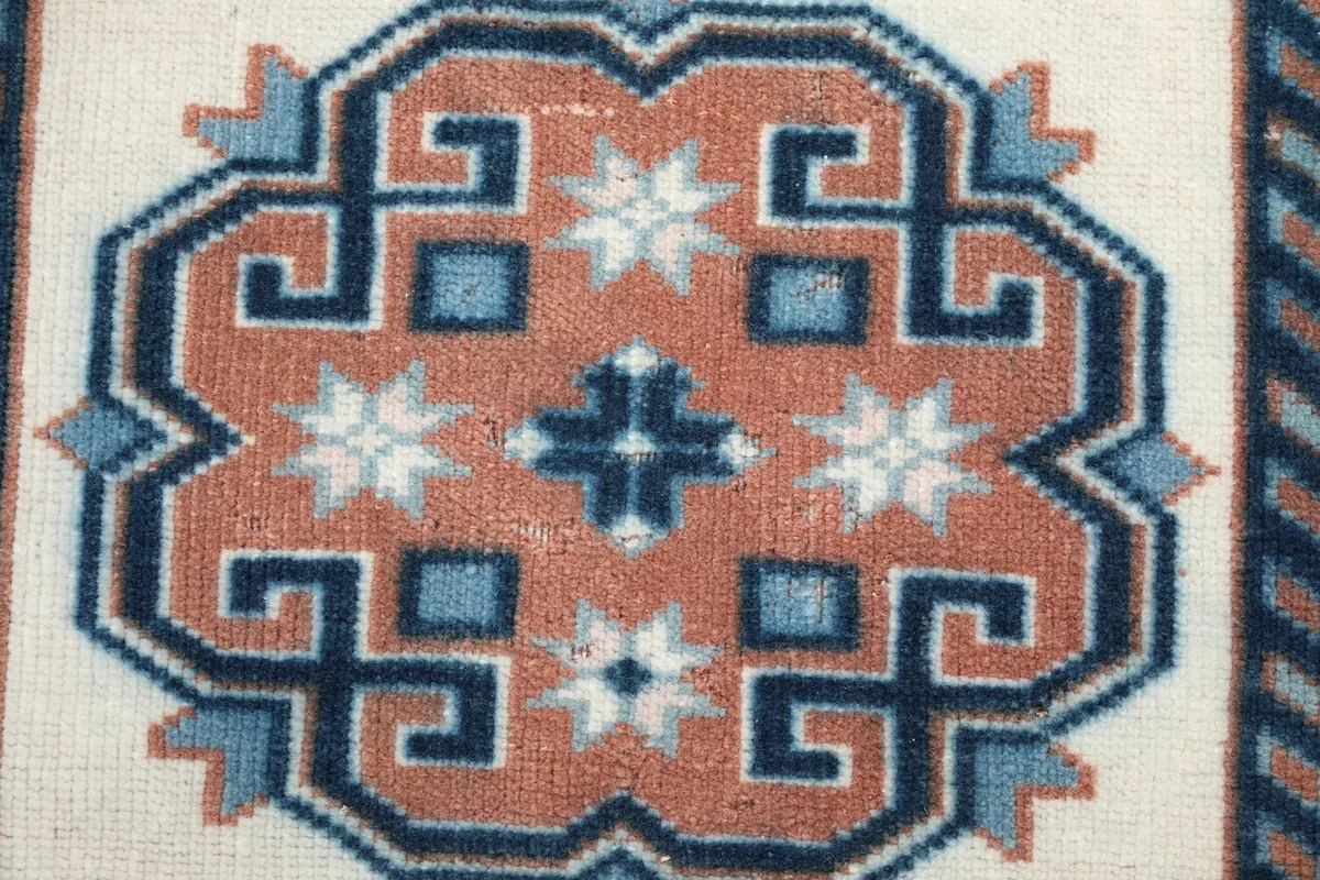 Detailed view of a rust geometric medallion with blue and ivory motifs within