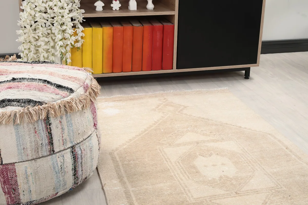 Close-up of the rug's texture and muted beige tones near a decorative ottoman.