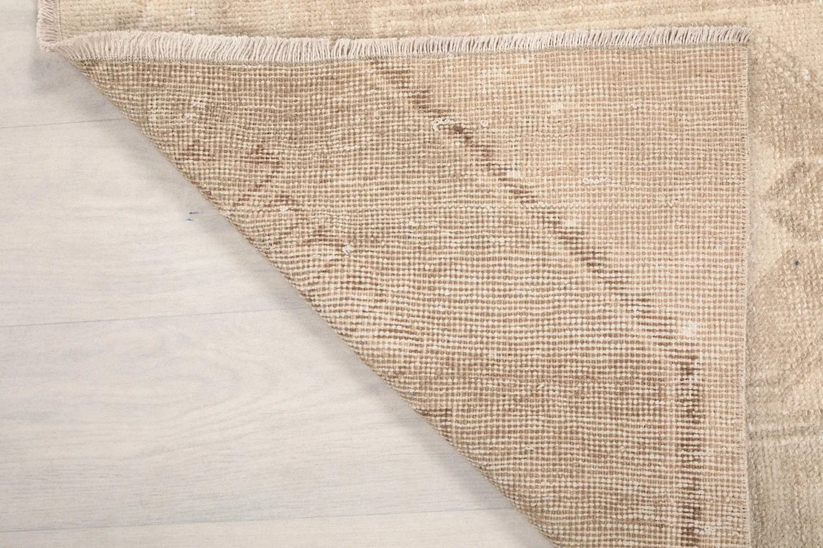 Folded corner of the rug showing the reverse side and the texture of the wool pile.